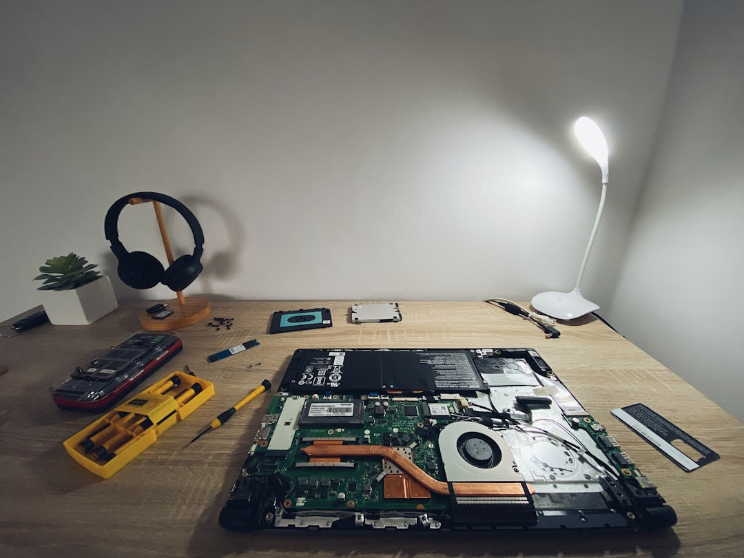 Disassembled laptop and repair tools on a wooden desk.